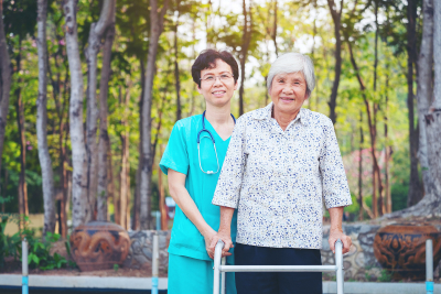 caregiver guiding a senior to walk